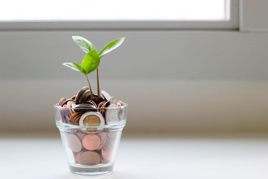 glass with coins out of which a plant is growing